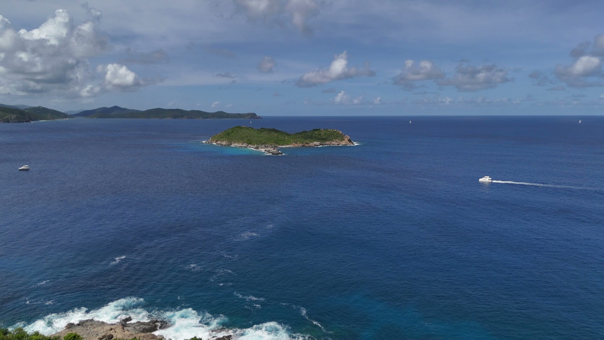 Aerial view of the British Virgin Islands with a yacht crossing open water